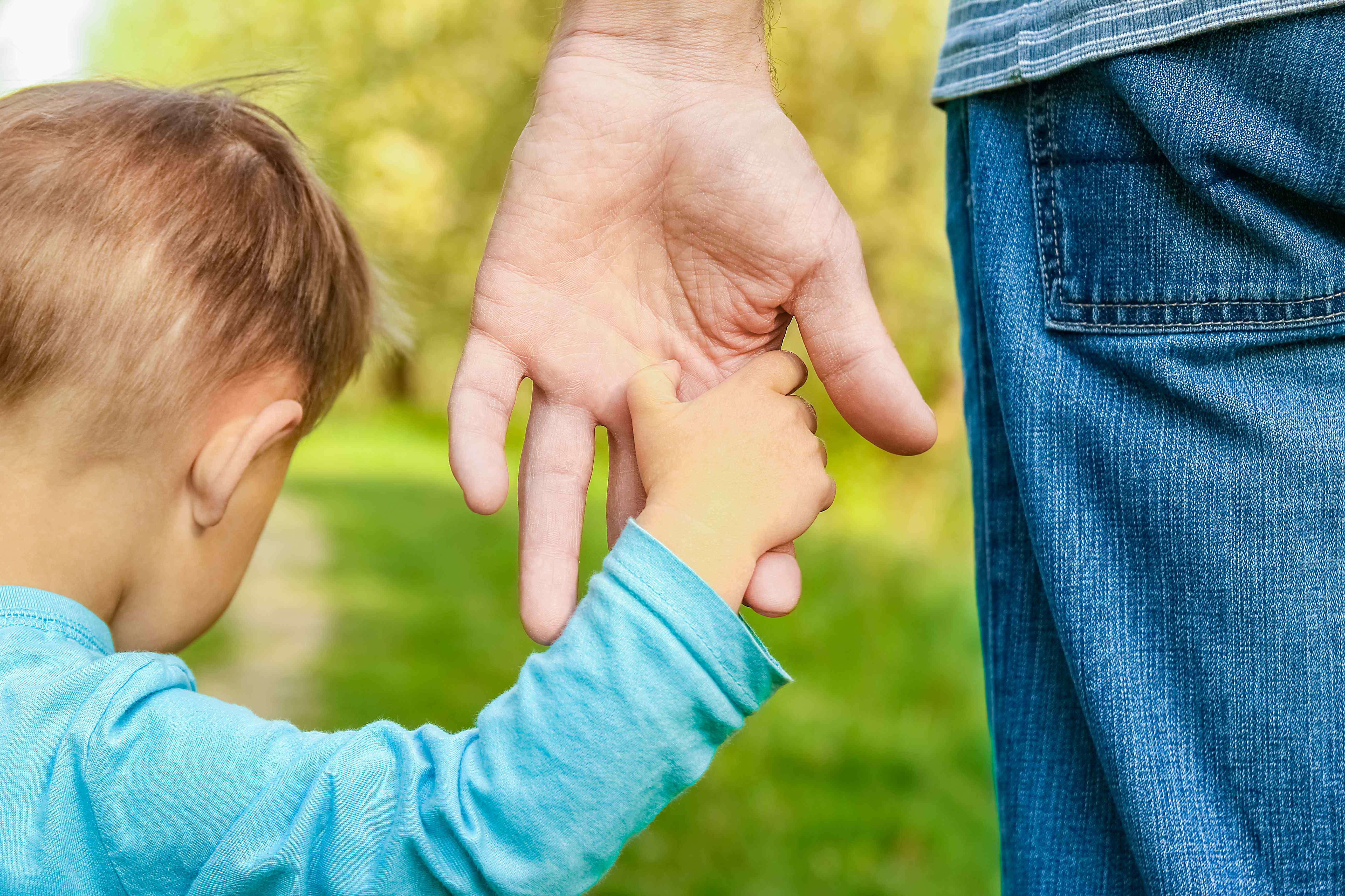 Elternhand hält Kinderhand als Symbol für Schutz und Vertrauen